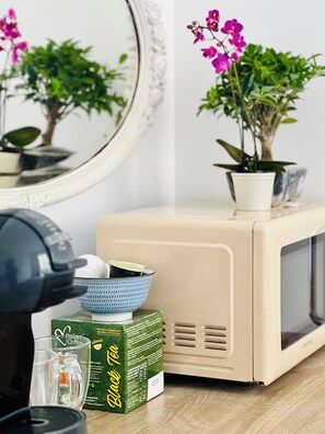 A retro-style microwave oven with a box of Italian coffee and a glass of water on a wooden surface. - New Listing (Paris)