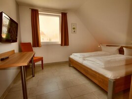 Una habitación pequeña y bien iluminada con una cama individual, un escritorio y una silla.