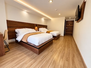 Ein modernes Hotelzimmer mit einem großen Bett, Nachttischen, einem an der Wand befestigten Fernseher und Holzböden.