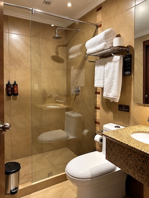 Ein modernes Badezimmer mit einer gläsernen Duschkabine, einer Toilette und einem Waschbecken mit Granitplatte.