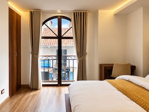 Ein Schlafzimmer mit einem Bett, einem Nachttisch und Blick auf einen Balkon mit Geländer.