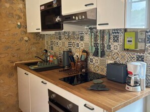 A compact kitchen with a built-in oven, a coffee maker, and a variety of utensils on the countertop. - House with private garden - 4 guests (SAINT POMPON)