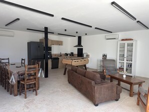 Un salon moderne comprenant un canapé, une table à manger et des chaises. Il y a également un coin cuisine avec un réfrigérateur, une cuisinière et des placards.