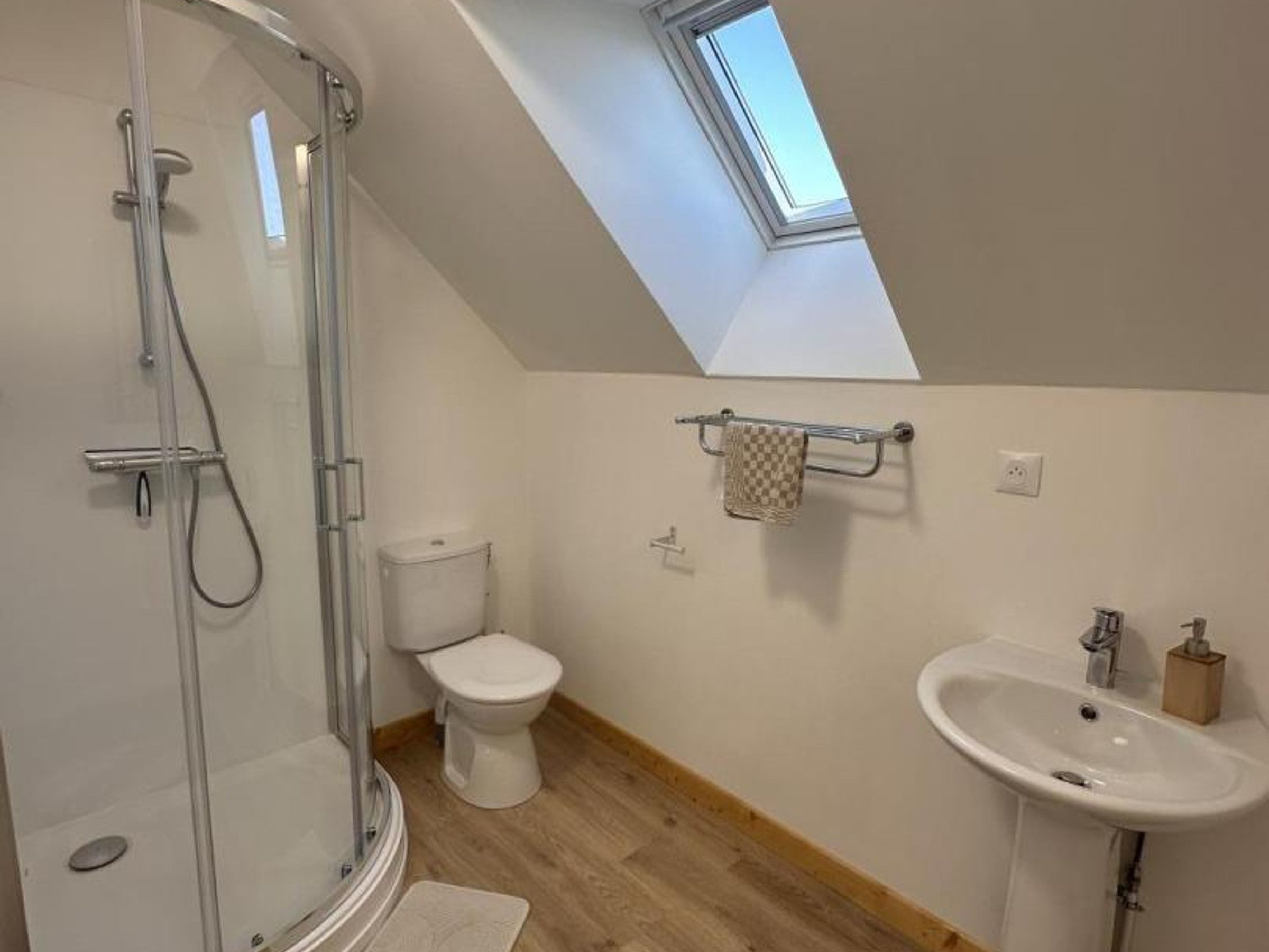 Een moderne badkamer met dakraam, douche, toilet en wastafel.