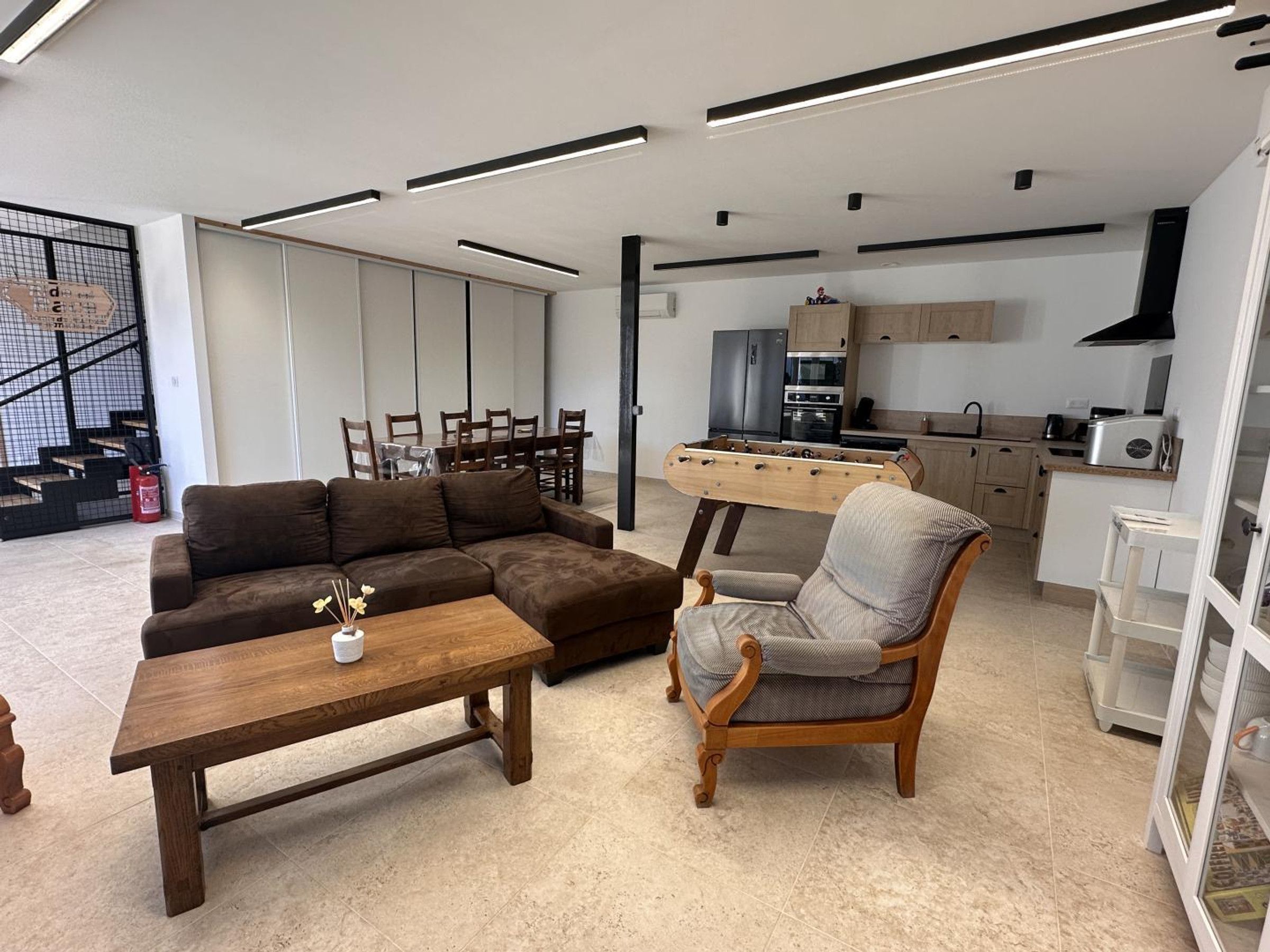 A modern living room with a sectional sofa, a wooden coffee table, and a classic armchair.