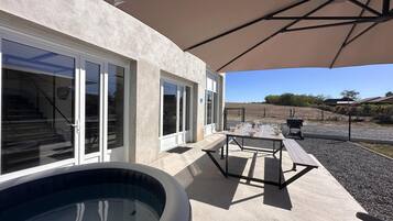 A poolside area with a hot tub, outdoor seating, and a covered patio.