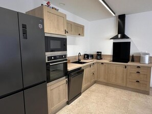 Eine moderne Küche mit Kühlschrank, Mikrowelle, Backofen und Kaffeemaschine.