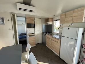 A compact kitchen with a refrigerator, stove, and sink. - Mobile home with AC - 6 guests (Arvert)