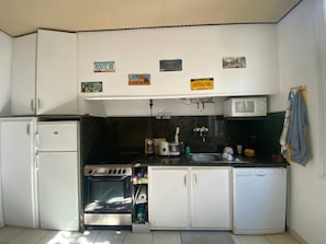 A compact kitchen with a refrigerator, stove, microwave, and sink. - Beachfront house, 6 guests (LES CABANES DE FLEURY)
