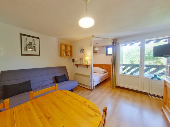 Ett rum med ett träbord, en soffa, en säng och en tv.