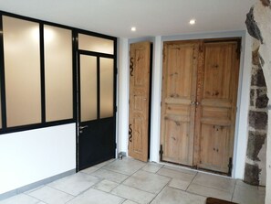 A room with a tiled floor, a black door with a frosted glass panel, and two wooden doors with metal handles. - Country house - Arsac-en-Velay (Arsac-en-Velay)