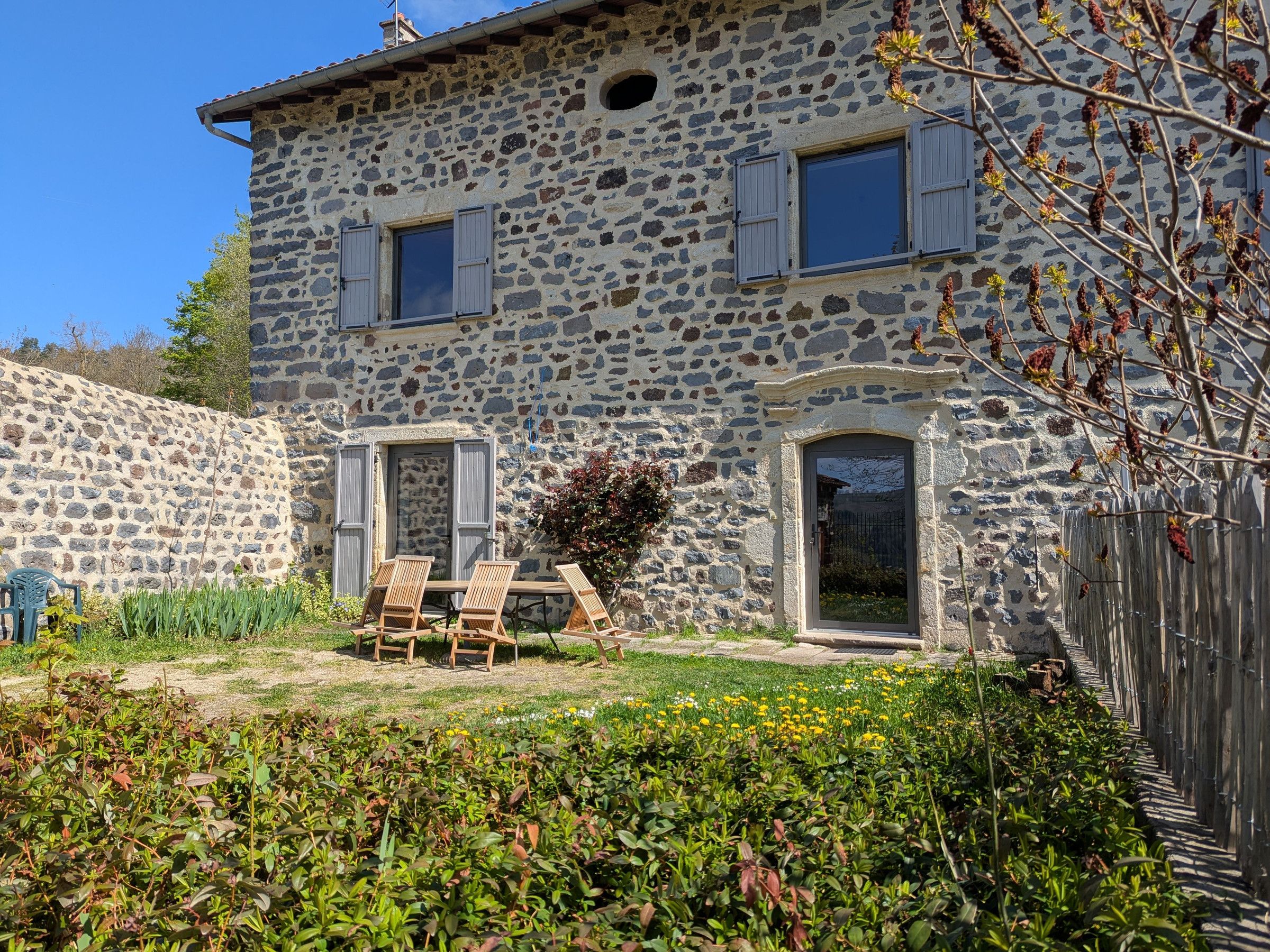 A stone building with a garden and outdoor seating area.