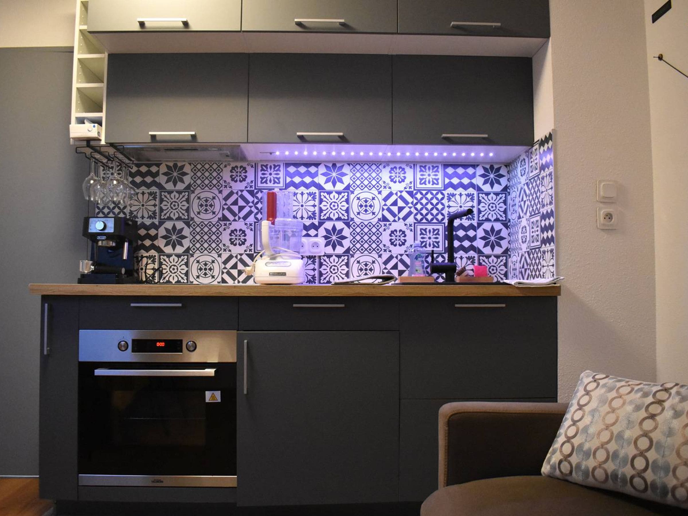 Una cocina compacta con horno empotrado, cafetera y un salpicadero decorativo.