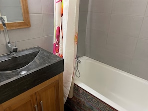 A bathroom with a black sink, wooden cabinet, white bathtub, and a shower curtain. - Studio in the center - 4 guests (Pralognan-la-Vanoise)