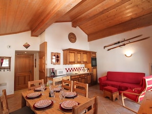 A cozy dining area with wooden furniture, a kitchen with wooden cabinets, and a red sofa. - Apartment with parking, pets OK - 6 guests (Crest-Voland)