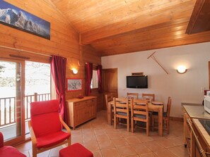 A wooden interior with a dining area, a TV mounted on the wall, and a window with curtains. - Apartment with parking, pets OK - 6 guests (Crest-Voland)