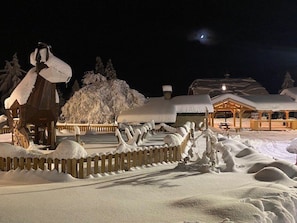 A snow-covered outdoor area with a wooden fence, a wooden structure with a roof, and a building with a covered porch. - Apartment with parking, pets OK - 6 guests (Crest-Voland)