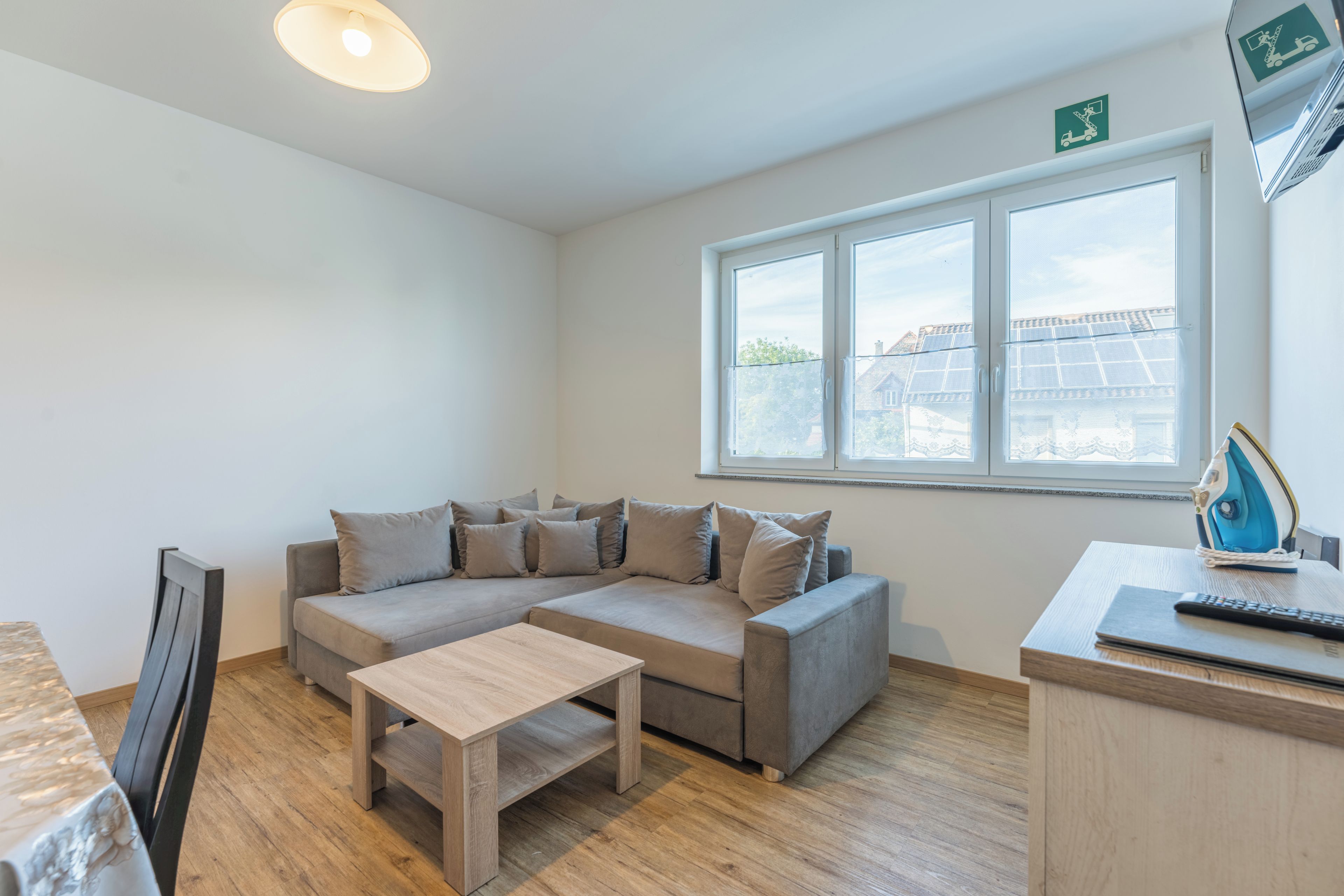 A modern living room with a sofa, a coffee table, and a window with a view of buildings.