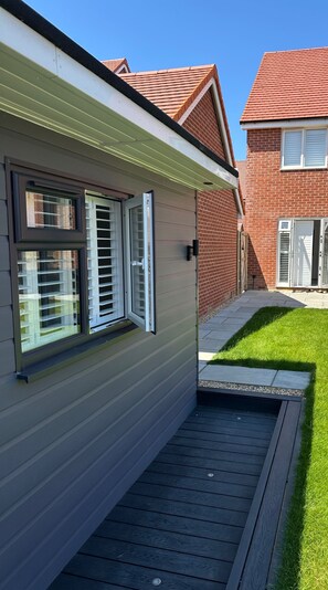 A residential building with a covered patio area, a brick facade, and a clear sky. - Apartment - Sleeps 2 - Parking - Garden - Seaside (Rochester)
