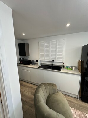 A modern kitchen with a built-in microwave, a coffee maker, and a sink. - Apartment - Sleeps 2 - Parking - Garden - Seaside (Rochester)