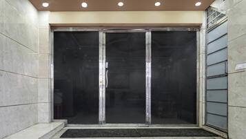 A hotel entrance with a glass door, a tiled floor, and a ceiling with recessed lighting.