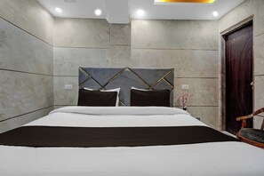 Un dormitorio moderno con cama, una puerta de madera y una lámpara fijada a la pared.