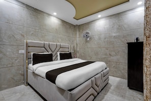 Un dormitorio moderno con una cama grande, un ventilador de techo y un armario oscuro.