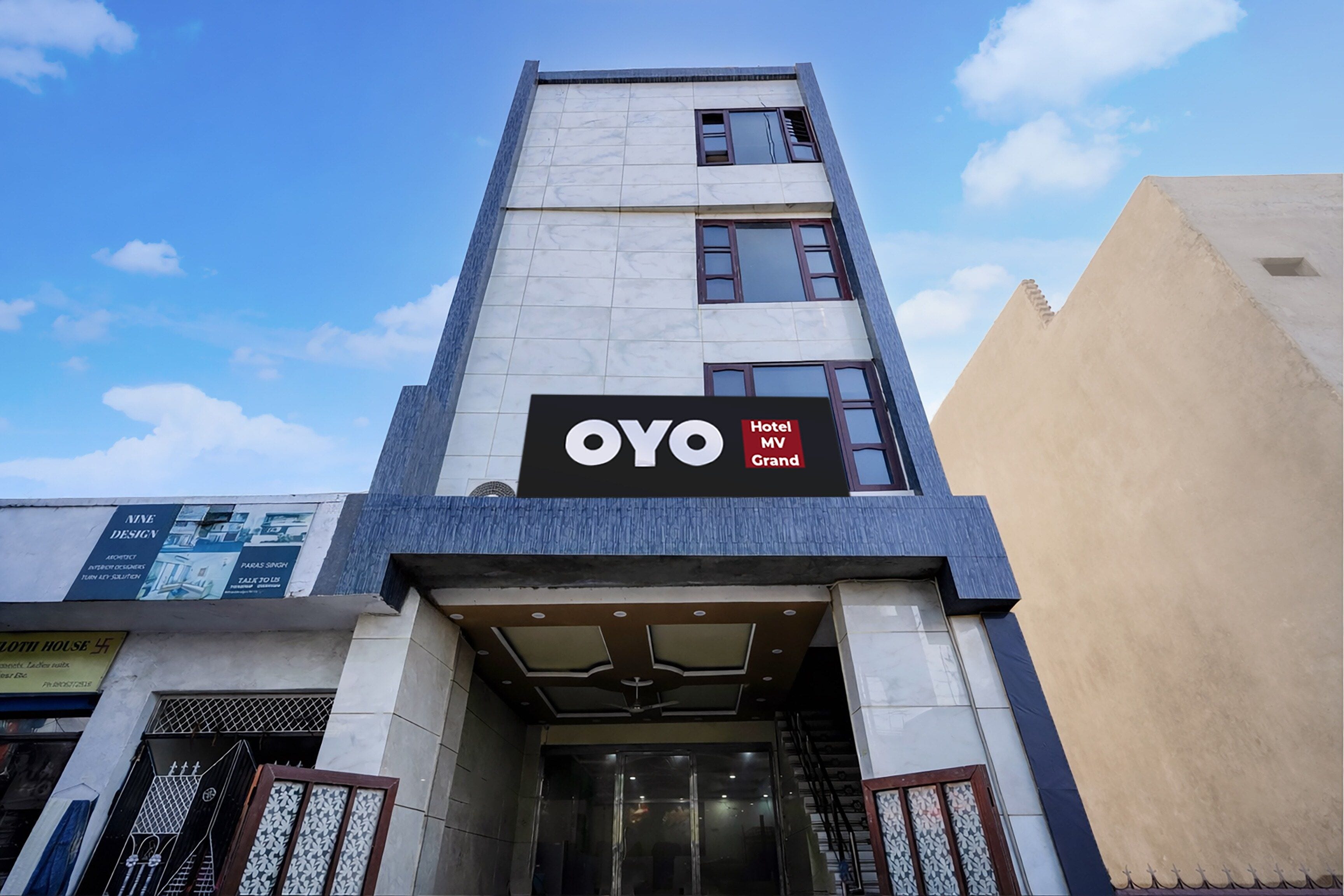A hotel entrance with a sign for 'OYO Hotel MV Grand'.