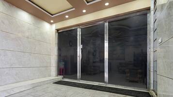 A hotel entrance with a tiled floor, a glass door, and a ceiling with recessed lighting.