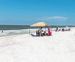 A beach scene with a covered area where people are gathered, a sandy beach, and the ocean in the background. - Spacious Coastal Home with Gulf View Balcony. 3 beach accesses & park. 3BR/3BA (Port St. Joe)