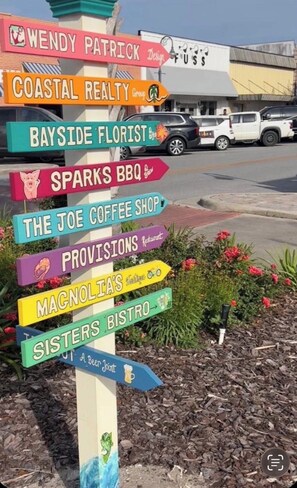 A colorful signpost with various business names pointing in different directions. - Spacious Coastal Home with Gulf View Balcony. 3 beach accesses & park. 3BR/3BA (Port St. Joe)