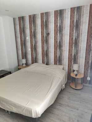 Ein Schlafzimmer mit einem Bett, Nachttischen und einer Wand mit vertikalen Holzbalken.