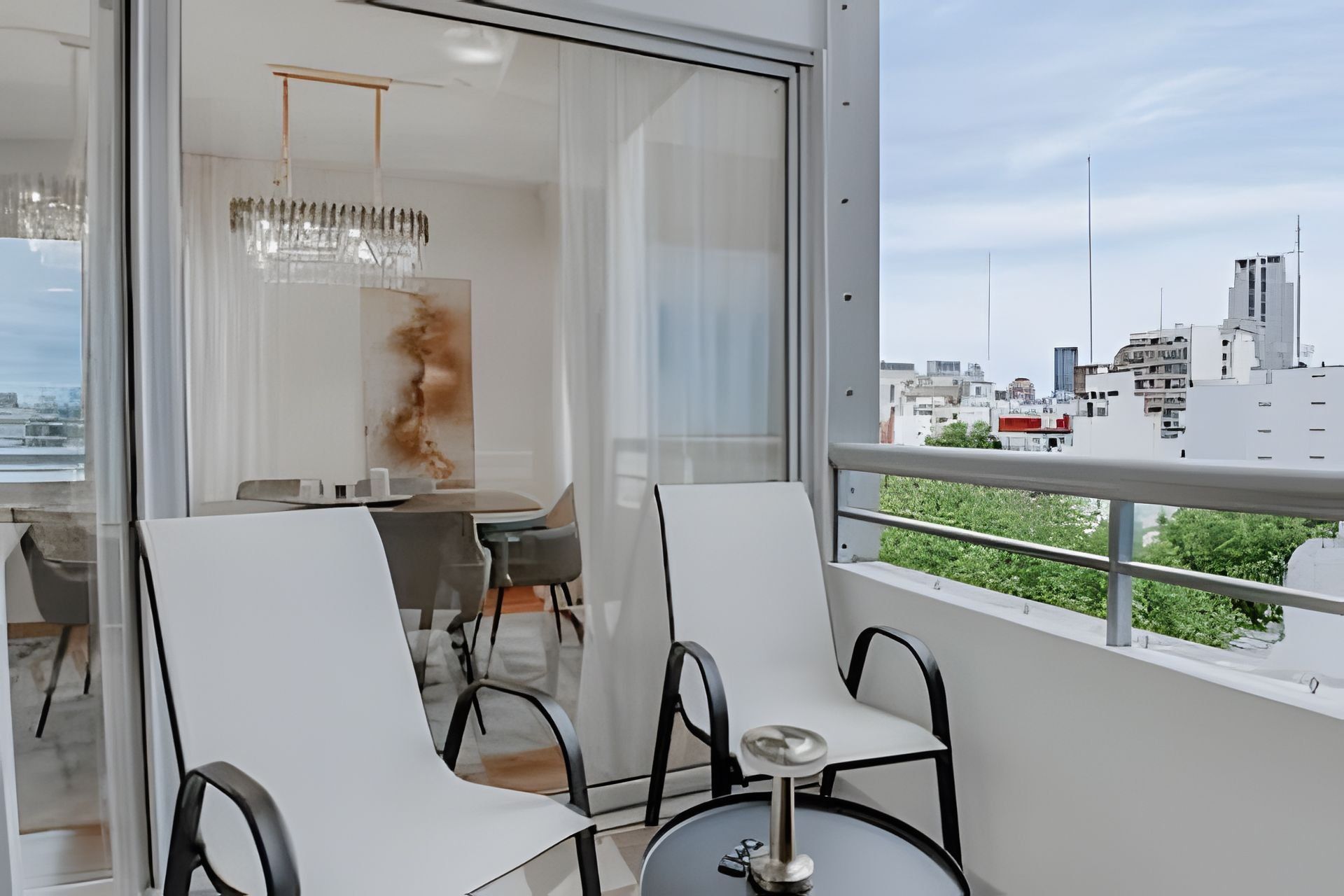 A modern interior with a dining area, a view of the cityscape, and a balcony with a railing.