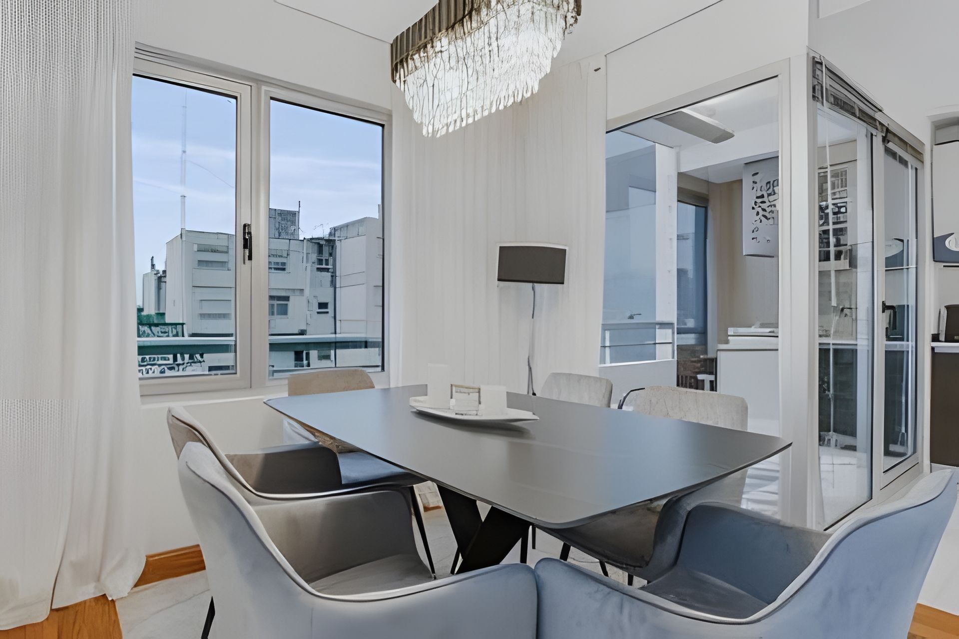 Un comedor moderno con una mesa rectangular, cuatro sillas y una lámpara de araña.