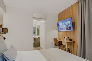 A hotel room with a bed, a desk with a chair, a mounted TV, and an air conditioning unit. - New with Full Amenities & BBQ in Palermo Soho (Buenos Aires)