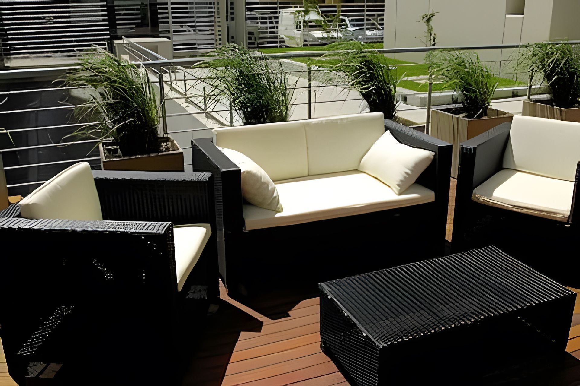 An outdoor seating area with a sofa and chairs, surrounded by potted plants.