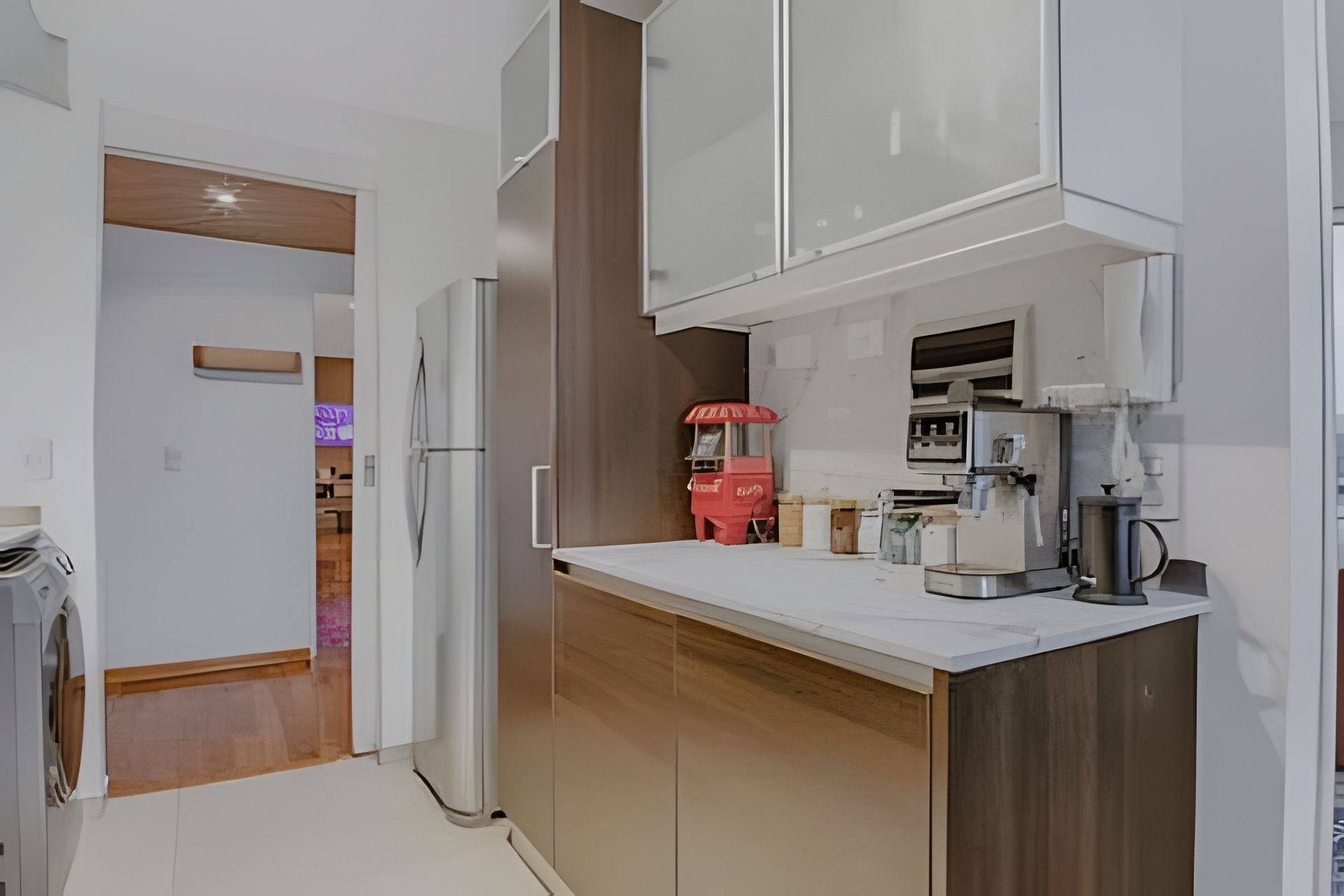 A modern kitchen with white cabinets, a wooden countertop, and a red vending machine.