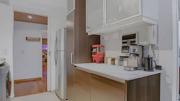 A modern kitchen with white cabinets, a wooden countertop, and a red vending machine.