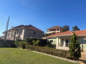 Un barrio residencial con casas de dos pisos, un césped cuidado y un cielo azul despejado.