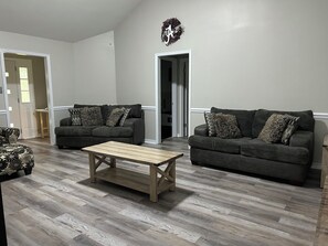 A living room with two dark-colored sofas, a wooden coffee table, and a patterned ottoman. - Enjoyable 3-bedroom house with AC in charming Mobile (Mobile)