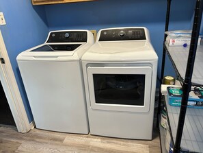 Two front-loading washing machines in a laundry room with a blue wall and wooden flooring. - Enjoyable 3-bedroom house with AC in charming Mobile (Mobile)