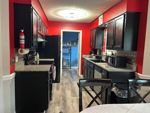 A compact kitchen with dark cabinets, a microwave, a coffee maker, and a fire extinguisher. - Enjoyable 3-bedroom house with AC in charming Mobile (Mobile)
