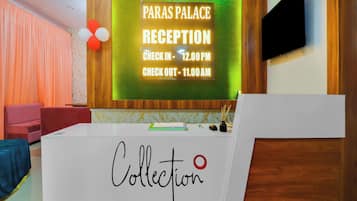 A reception desk with a sign indicating the check-in and check-out times for Paras Palace.
