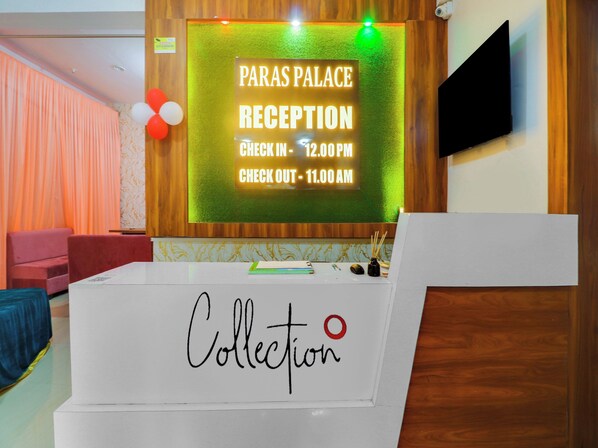 A reception desk with a sign indicating the check-in and check-out times for Paras Palace.