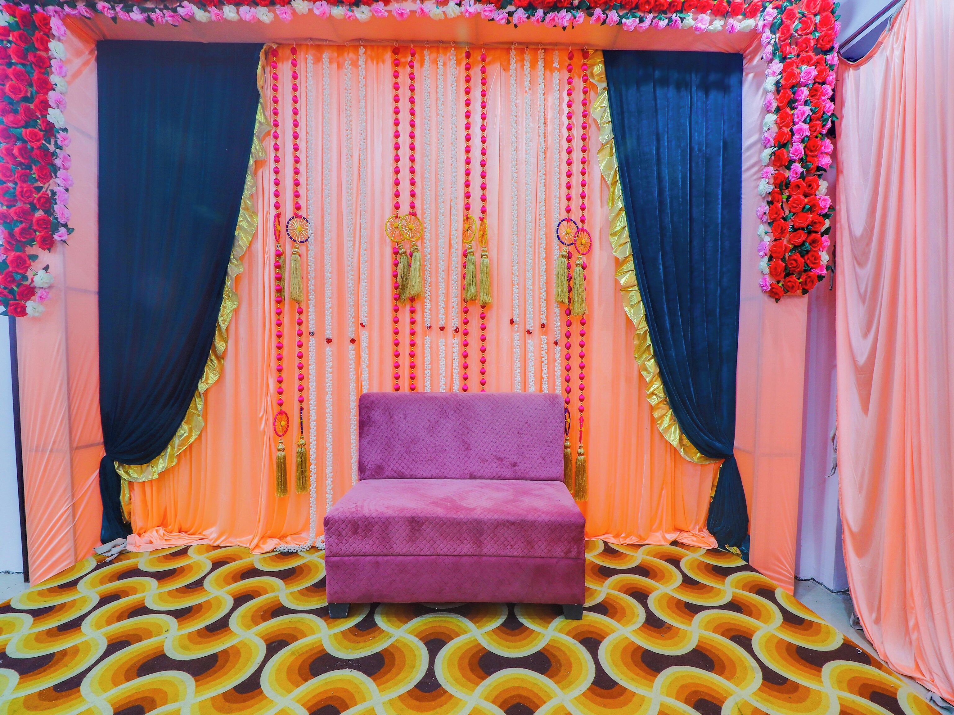 A room with a patterned floor, a purple bench, and draped curtains with floral decorations.