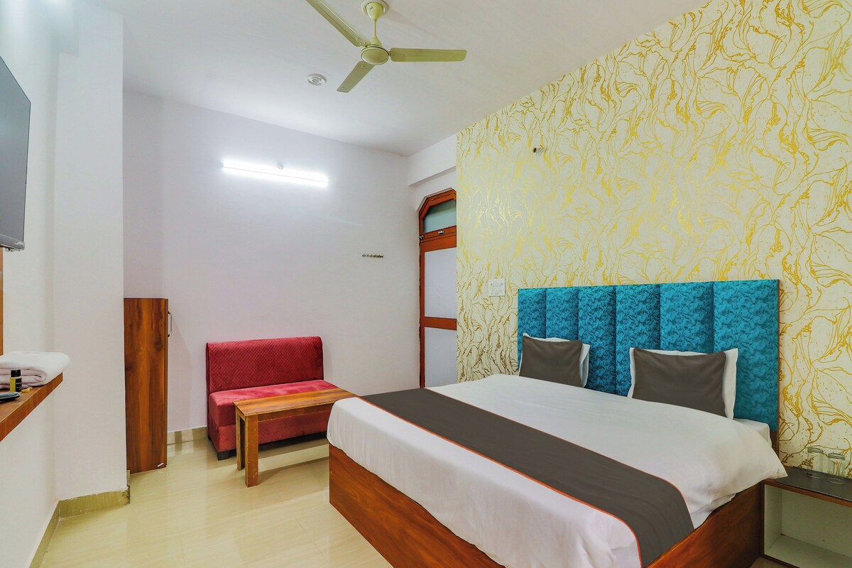 A hotel room with a bed, a red bench, a wooden nightstand, and a ceiling fan.
