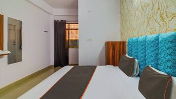 Habitación de hotel con cama, armario, espejo y ventana con cortinas.