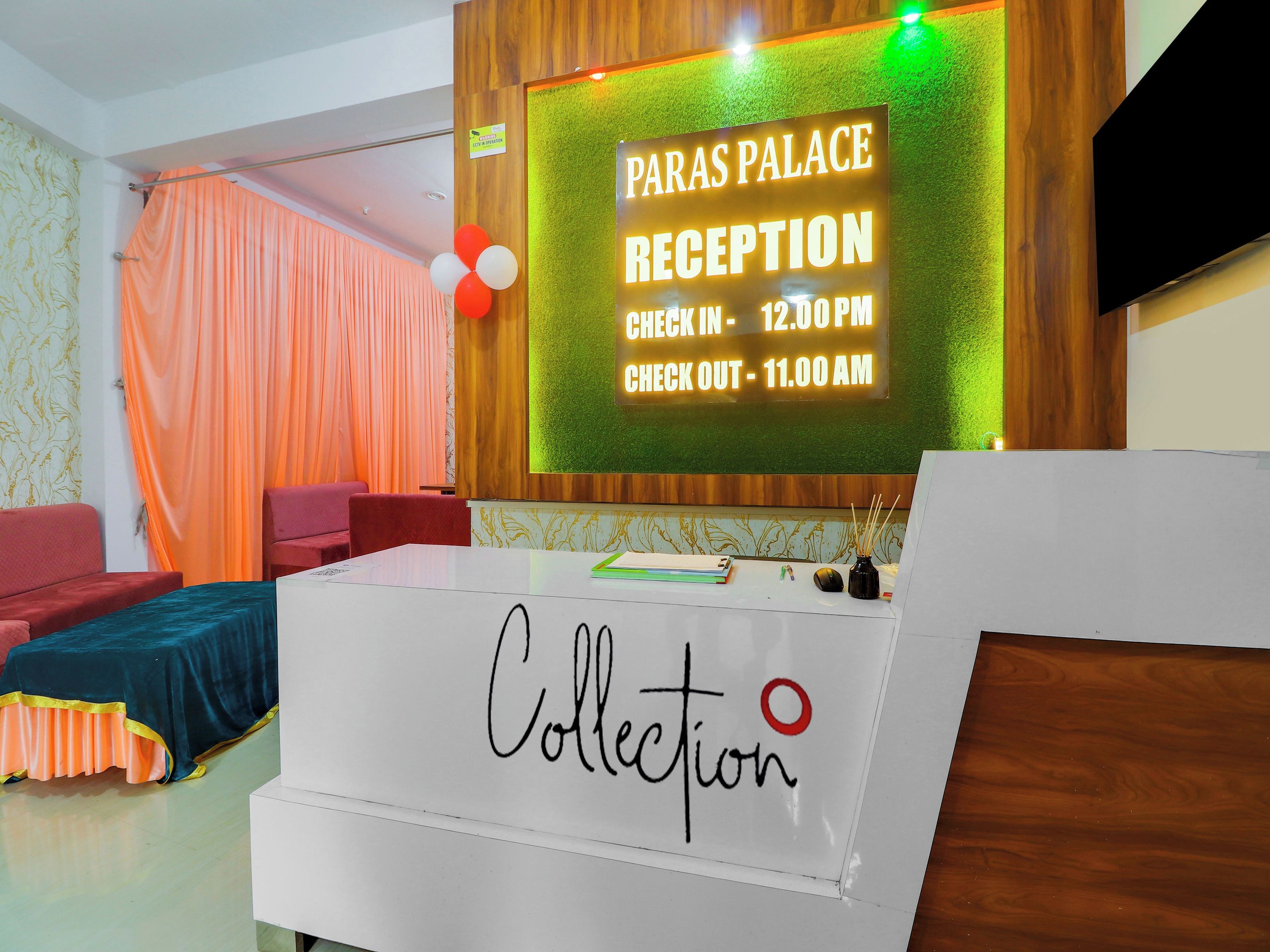 Mostrador de recepción con un cartel que indica 'Paras Palace Reception' y horarios de registro de entrada y salida.