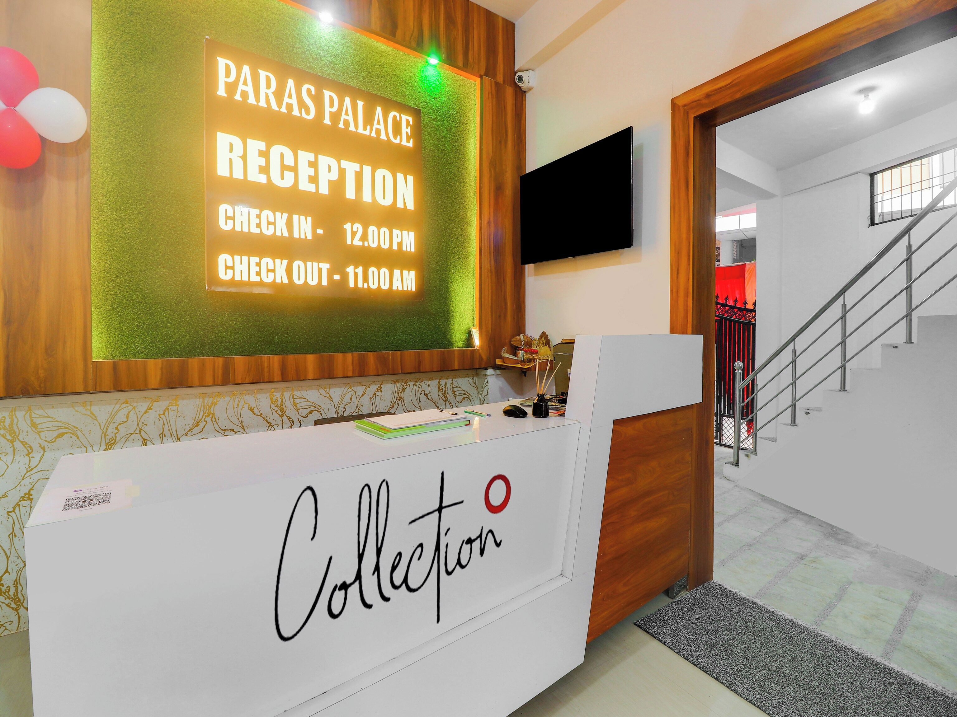 Un comptoir d’accueil avec un panneau indiquant les heures d’arrivée et de départ de l’hôtel « Paras Palace ».