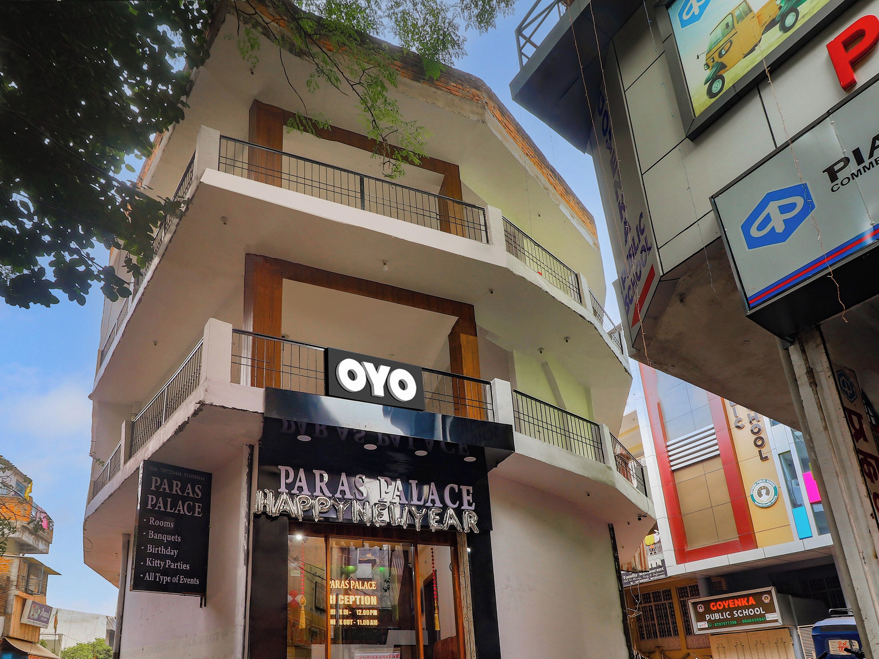 Un edificio de varios pisos con un letrero que indica 'OYO' y 'Paras Palace', señalando un hotel o espacio para eventos.